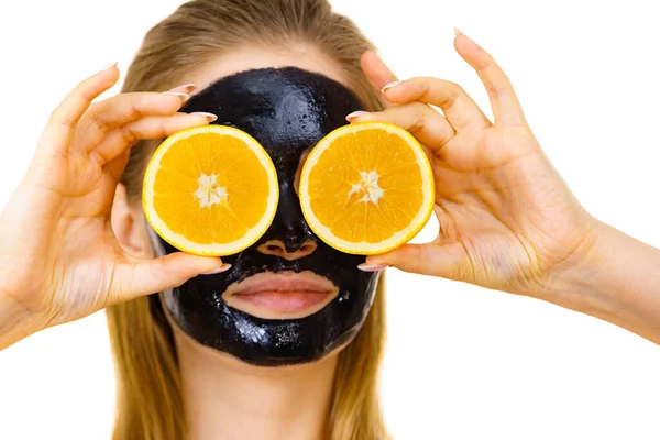 Girl black carbo mask on face holds orange fruit — Stok Foto