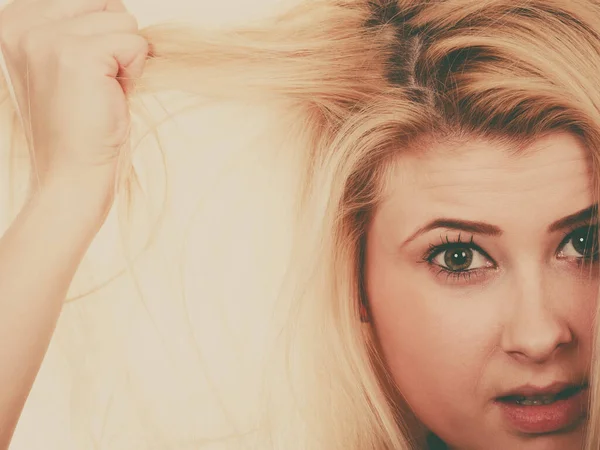 Blond kvinne som holder sitt tørre hår – stockfoto