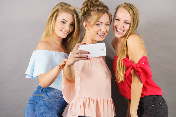 Fashionable women taking selfie self picture using smartphone having fun enjoying friends time.