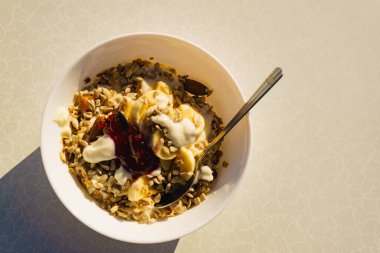 Sağlıklı kahvaltı yoğurt ile yulaf ezmesi granola, muz meyve ve kase ayçiçeği tohumu, güneşli sabah
