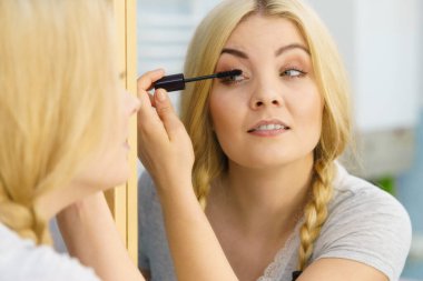 Makyajını siyah rimel sürerek yapan bir kadın kirpiklerini fırçalıyor. Kadın güzellik çehresi konsepti.