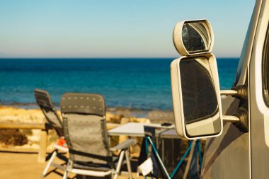 Kamp arabası ve İspanyol deniz kıyısında sandalyeli turist masası. Deniz kenarında kamp yapmak. Tatil ve seyahat.