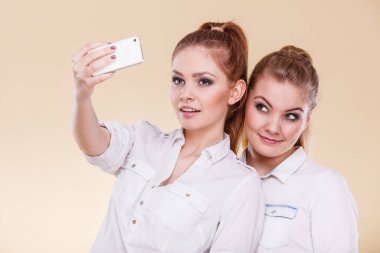 Eğlenceli bağ selfie kavramı. Kız ya da en iyi arkadaş, akıllı telefon kamera ile kendini fotoğrafta iki öğrenci sarışın kızlar eğleniyor