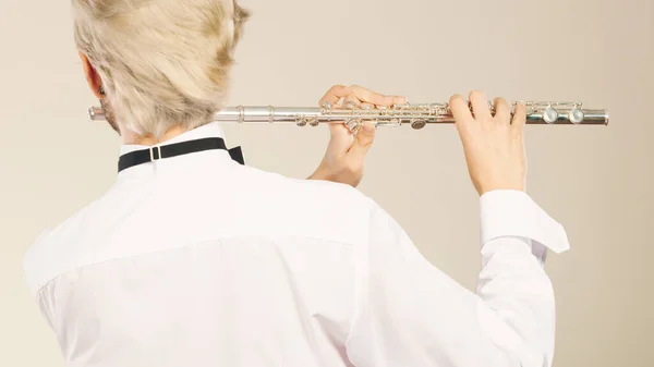 Flute music playing professional male flutist musician performer. Young elegant stylish man with instrument