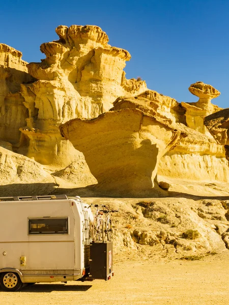 Camper car on parking area at eroded yellow sandstone formations, Enchanted City of Bolnuevo, Murcia Spain. Tourist attraction.