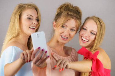 Moda kadınları, akıllı telefon kullanarak kendi resimlerini çekiyorlar. Arkadaşlık zamanlarının tadını çıkarıyorlar..
