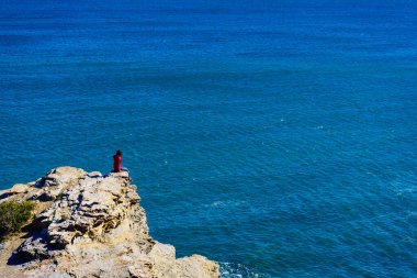 Murcia bölgesindeki İspanyol kayalık kıyı şeridindeki turist kadın. Akdeniz kıyısı manzarası, Calblanque Bölgesel Parkı.