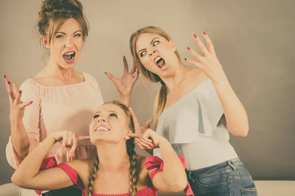 Woman being bullied by her two female friends. Women having argument. Angry fury girls screaming at her friend or younger sister. Friendship difficulties, rivaly and envy problems.