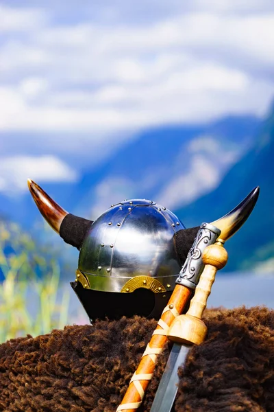 Viking helmet with weapons on fjord shore in Norway. Tourism and traveling concept