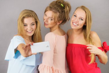 Moda kadınları, akıllı telefon kullanarak kendi resimlerini çekiyorlar. Arkadaşlık zamanlarının tadını çıkarıyorlar..
