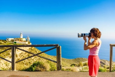 Kameralı kadın turist Mesa Roldán deniz fenerinden fotoğraf çekiyor. Cabo de Gata Nijar Doğal Parkı, Endülüs İspanya.