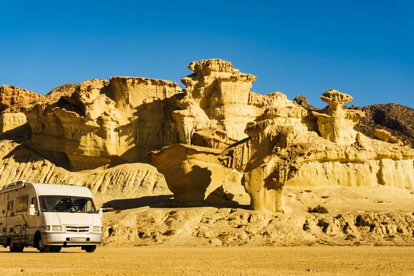 Camper car on parking area at eroded yellow sandstone formations, Enchanted City of Bolnuevo, Murcia Spain. Tourist attraction.