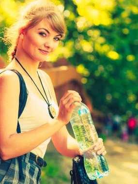 Macera, turizm, yaz tatilinin tadını çıkarmak. Sırt çantalı, orman yolunda su şişesi olan genç turist kadın.