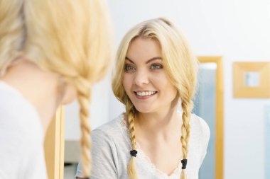 Güzel bir kadın, sarı saçlarında iki sevimli örgü var. Saç bakımı ve kuaförlük konsepti.