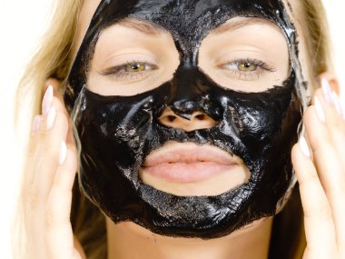 Yüzünde karbonhidratlı siyah kabuk soyma maskesi olan genç bir kadın. Kozmetik, beyazın üzerinde çıkarmaya hazır. Yağlı ciltle ilgilenen genç bir kız. Güzellik tedavisi. Cilt bakımı.