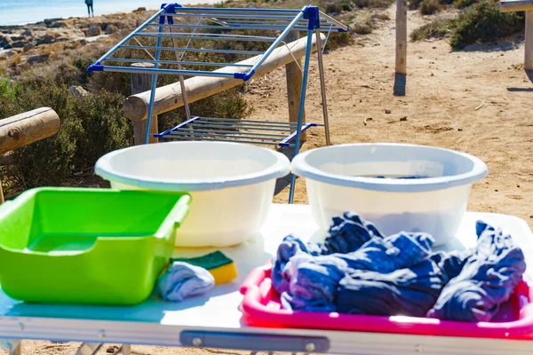 Washing clothing laundry outdoor at campsite. Bowl with soap water and laundry dryer. Camping