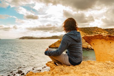 Cocedores Sahili 'nin sarı kum oluşumlarında dinlenen yetişkin turist kadın. Akdeniz, Murcia bölgesi İspanya.