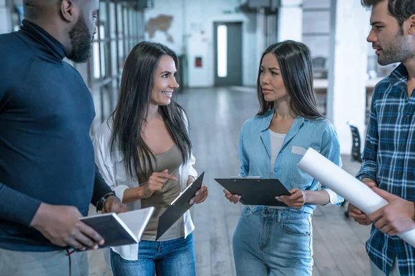 Best team ever. Group of young multi ethnic business people in smart casual wear working together and smiling while standing in the middle of the office