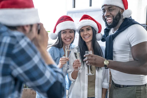 Merry Christmas and Happy New Year 2020.Young creative people are celebrating holiday in modern office.Office workers posing for a photographer at a corporate event. Successful freelancers team