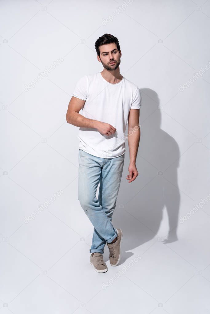 So serious. Full length of handsome young man in casual wear looking at camera while standing against grey background