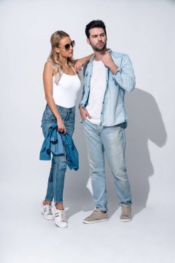 Harika görünüyorsun. Gri arka planda ayakta duran genç ve güzel çiftin tam boyu.