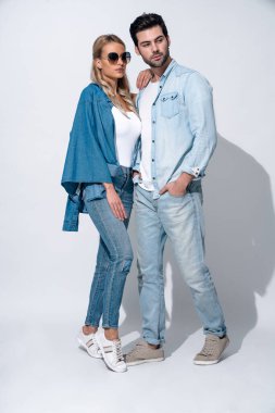 Harika görünüyorsun. Gri arka planda ayakta duran genç ve güzel çiftin tam boyu.