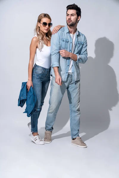 Looking amazing. Full length of beautiful young couple bonding while standing against grey background