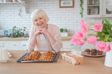 Aşkla yemek pişirmek. Mutfakta yemek pişiren çekici yaşlı kadın. Neşeli büyükanne yemek yapıyor..