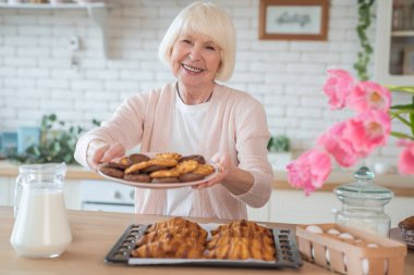 Aşkla yemek pişirmek. Mutfakta yemek pişiren çekici yaşlı kadın. Neşeli büyükanne yemek yapıyor..