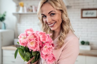 Kızının mutfakta sunduğu bir buket lale çiçeğiyle sevimli bir kız.