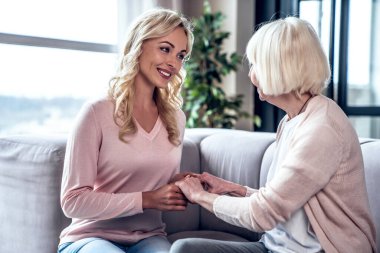 Kıdemli kadın ve çekici kızı evde birlikte vakit geçiriyorlar ve kanepede oturuyorlar. Anneler Günün kutlu olsun.