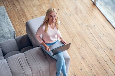 Çekici genç bir kadın evde vakit geçiriyor. Dizüstü bilgisayarla kanepede otururken dinleniyorum.