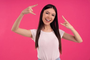 Hoş görünümlü, neşeli bir kadın, iki eliyle de rock işareti yapıyor, isyankar hissediyor, heavy metal gösteriyor, çıldırıyor, evde yüksek sesle müzik dinliyor, gündelik giyiniyor. Asyalı kız partide eğleniyor..