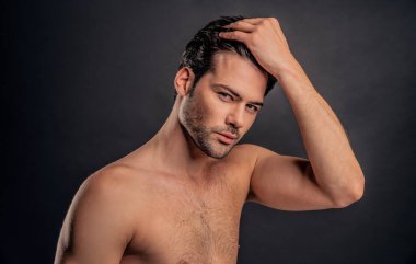 Her şey mükemmel olmalı. Yakışıklı genç adam saçlarını tarıyor ve gri arka planda dururken gülümsüyor..