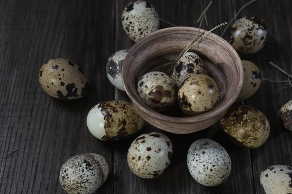 Quail eggs in clay pot on dark background