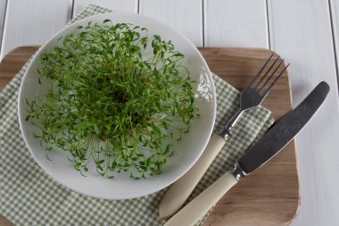 Garden cress çatal ve bıçak beyaz tabakta. Sağlıklı vejetaryen yemek