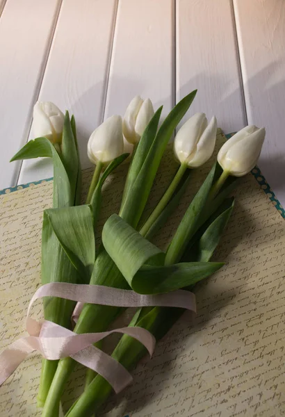 White tulips on white wooden background.