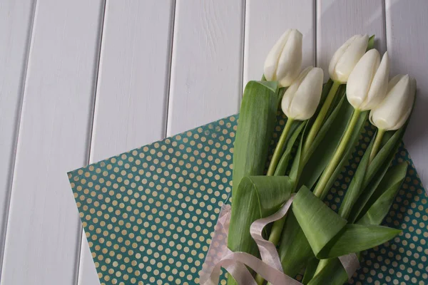 White tulips on white wooden background.