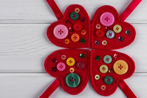 Corazones de fieltro rojo artesanías decoradas con cuentas y botones sobre fondo blanco — Foto de Stock