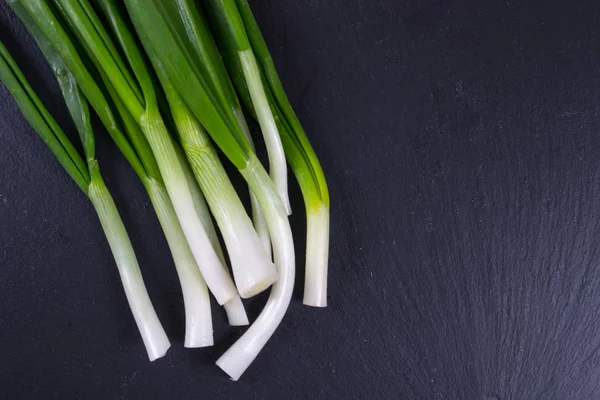 Grüne Zwiebel auf der schwarzen Schiefertafel — Stockfoto