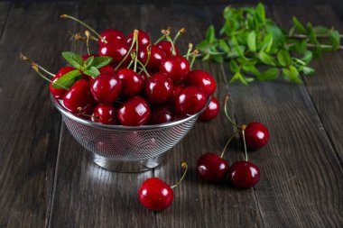 Koyu ahşap zemin üzerine metal elek otlar taze kiraz.