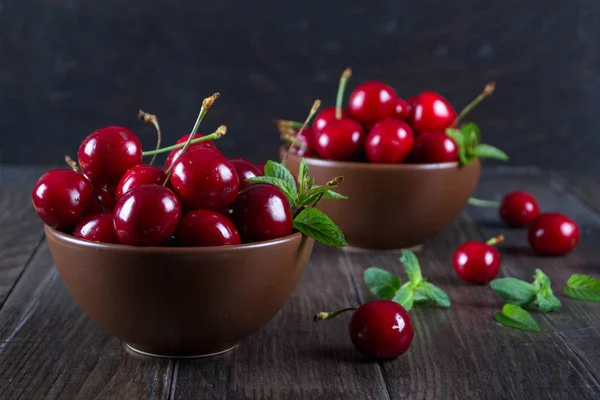 Fresh cherries in  clay bowl on  dark table — Stock Photo, Image