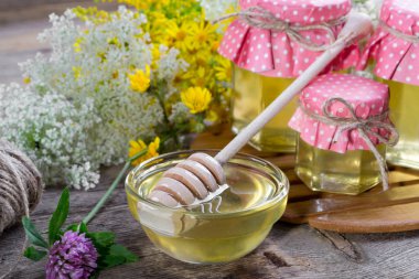 Doğal ışık sıvı bal. Cam Kavanoz ve çiçekli beyaz arka plan üzerinde Kepçe tatlım.