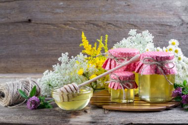 Taze sıvı bal tencere ve bal yaz kır çiçekleri rustik ahşap masa üzerinde sopa