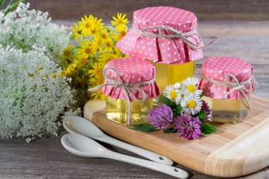 Beyaz masa üzerinde bir kavanoz, çiçekler ve bal ayı'yı tatlım