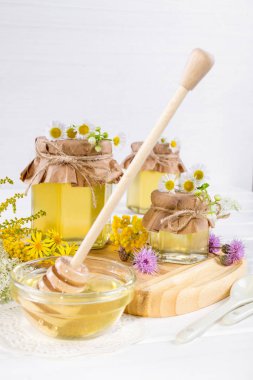 Doğal ışık sıvı bal. Cam Kavanoz ve çiçekli beyaz arka plan üzerinde Kepçe tatlım.
