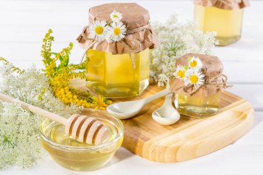 Beyaz masa üzerinde bir kavanoz, çiçekler ve bal ayı'yı tatlım