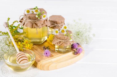 Beyaz masa üzerinde bir kavanoz, çiçekler ve bal ayı'yı tatlım