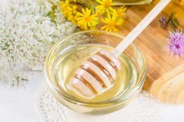 Doğal ışık sıvı bal ve çiçekli beyaz arka plan üzerinde Kepçe