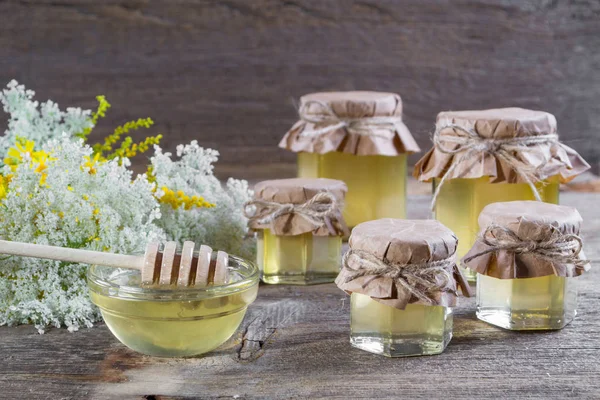 Méz jar, a virágok és a méz merítő munkás, a fehér asztal az — Stock Fotó